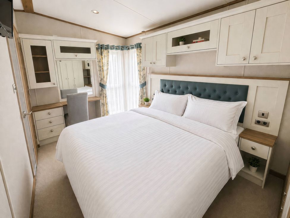 A bedroom with a bed and dresser at Caravan i35 in Conwy