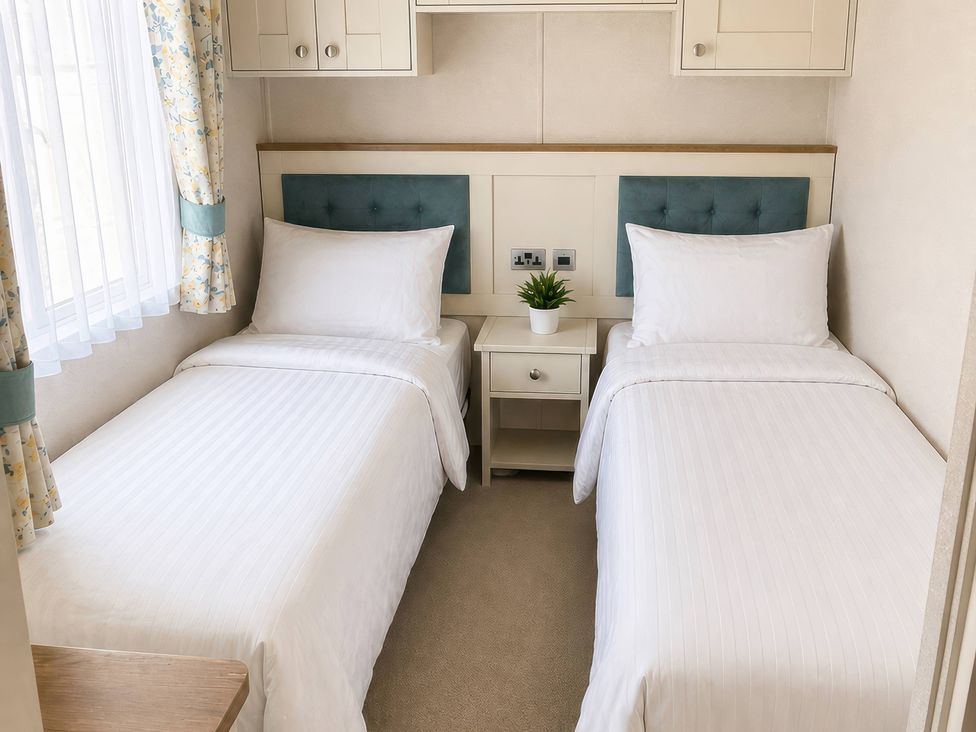 A bedroom with two single beds and a nightstand at Caravan i35 Conwy