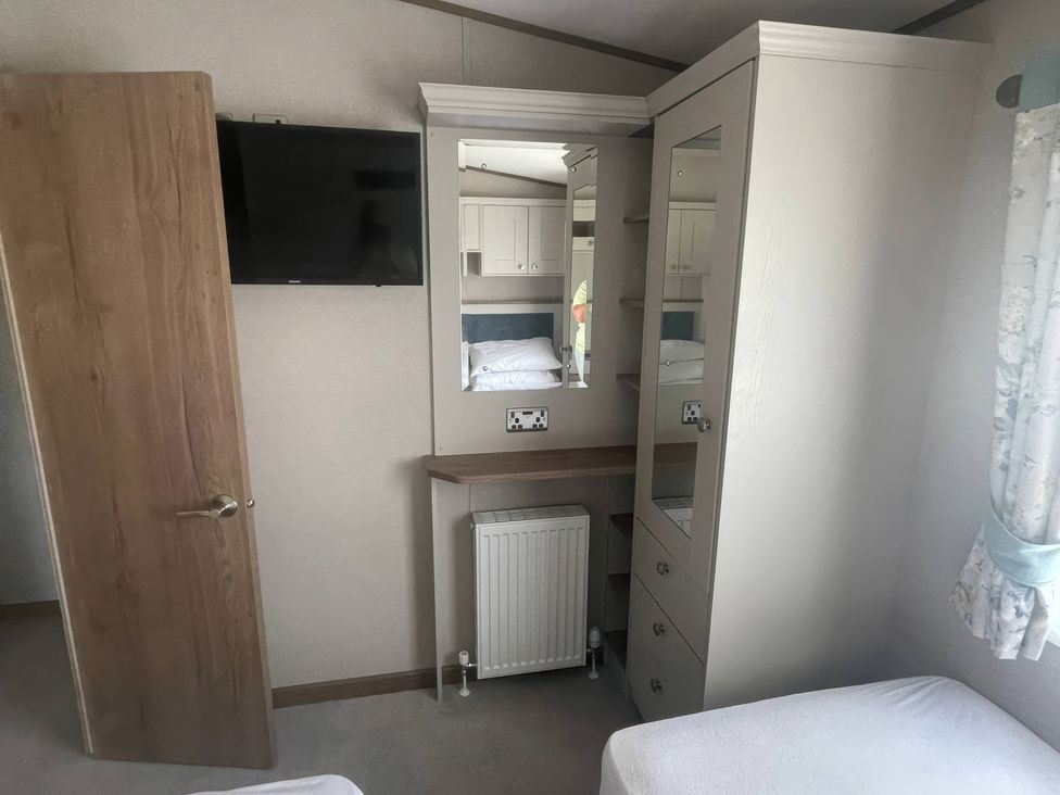 A bedroom with a television and wardrobe at Caravan i35 in Conwy