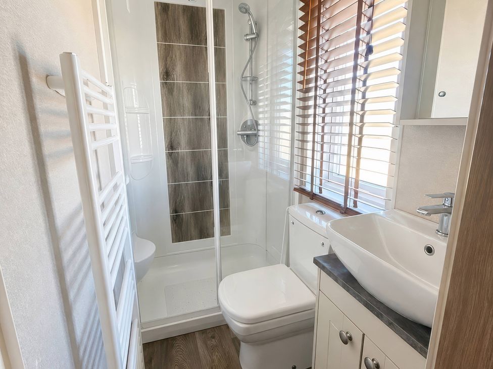A bathroom with a shower, toilet, and sink at Caravan i35 Conwy