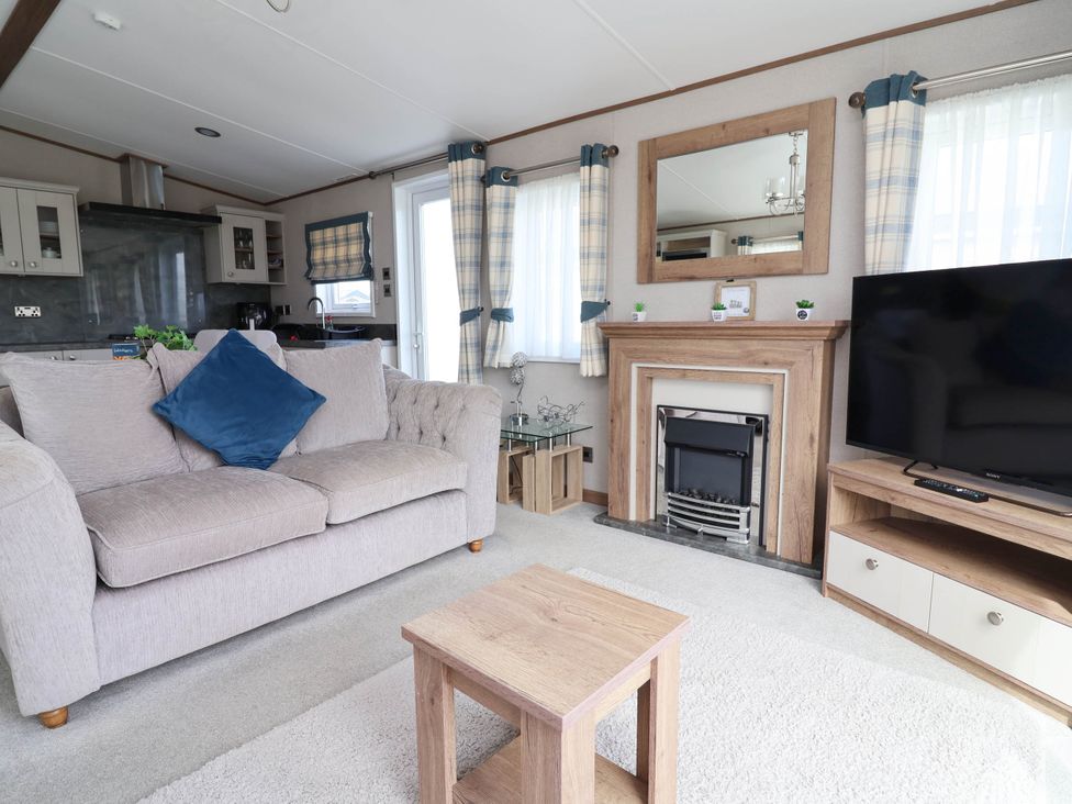 A living room with a sofa and television at Caravan i35 Towyn