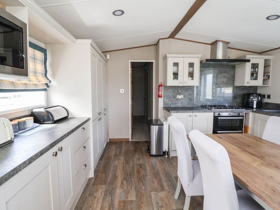 A kitchen with appliances and dining area at Caravan i35 Towyn