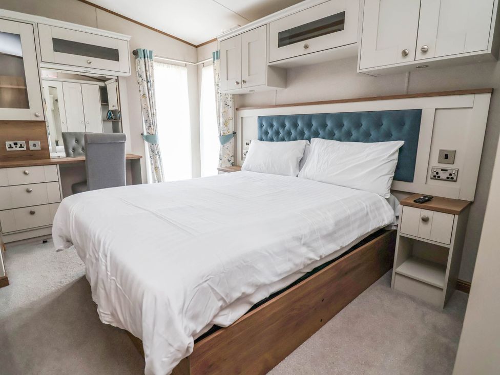 A bedroom with a bed and a dressing area at Caravan i35 Towyn