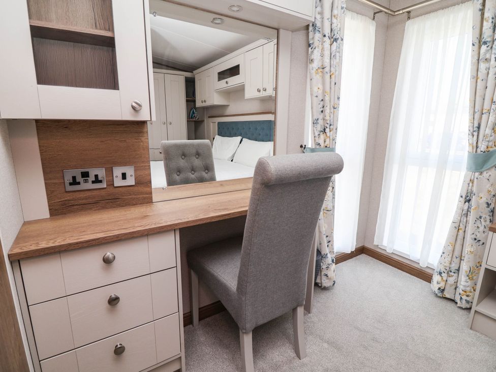 A bedroom with a desk and a chair at Caravan i35 Towyn