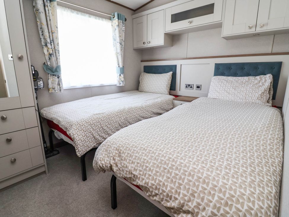 A bedroom with two beds and a wardrobe at Caravan i35 Towyn