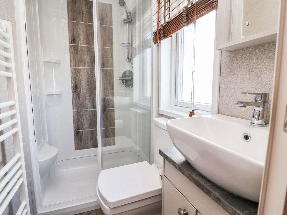 A bathroom with shower, toilet, and sink at Caravan i35 Towyn