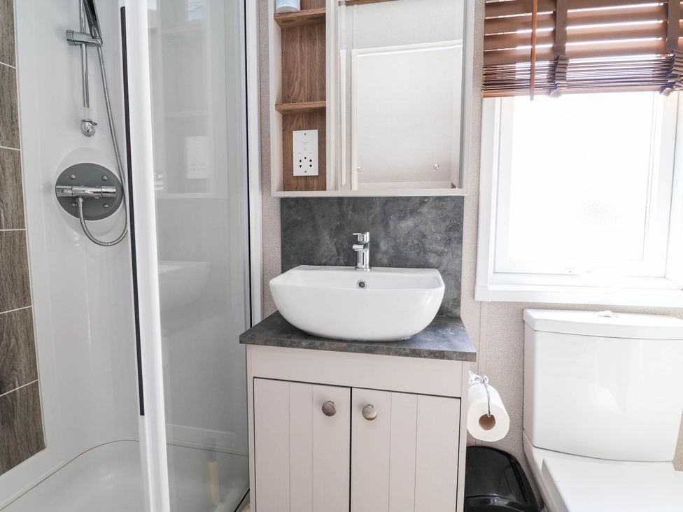 A bathroom with a shower, sink, and toilet at Caravan i35 Towyn