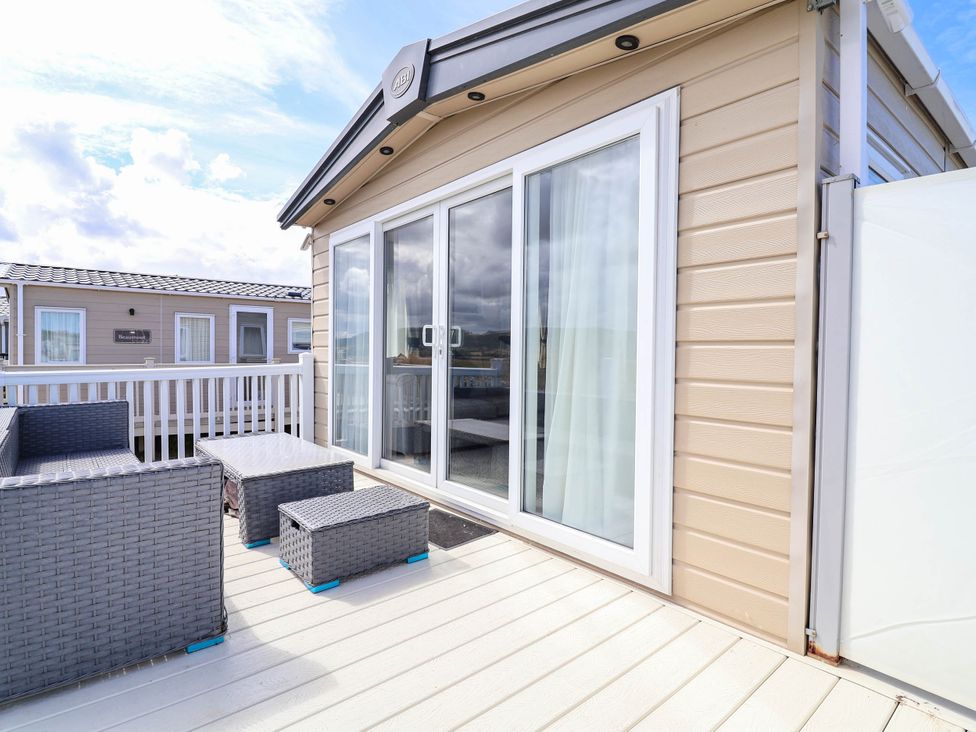An outdoor patio with chairs and a table at Caravan i35 in Towyn