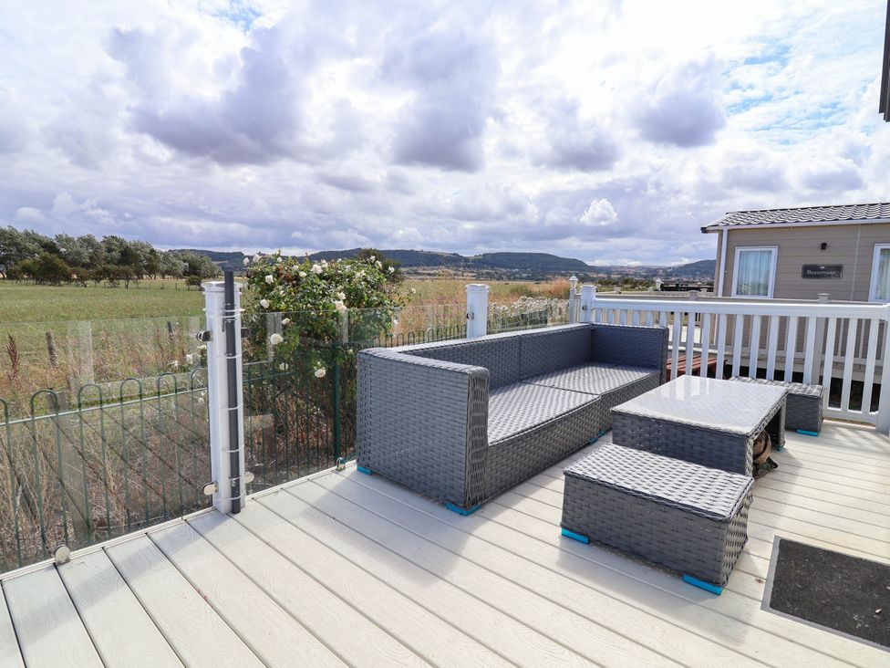 An outdoor sitting area with a sofa and coffee table at Caravan i35 in Towyn