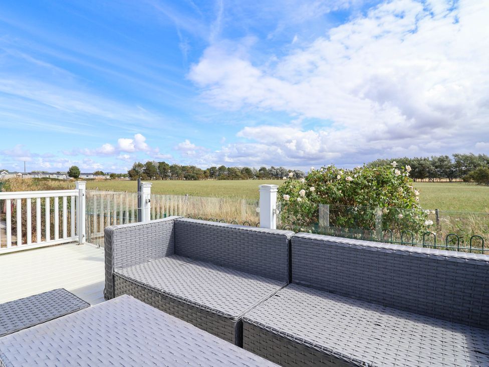 An outdoor seating area with a view of the field at Caravan i35 Towyn