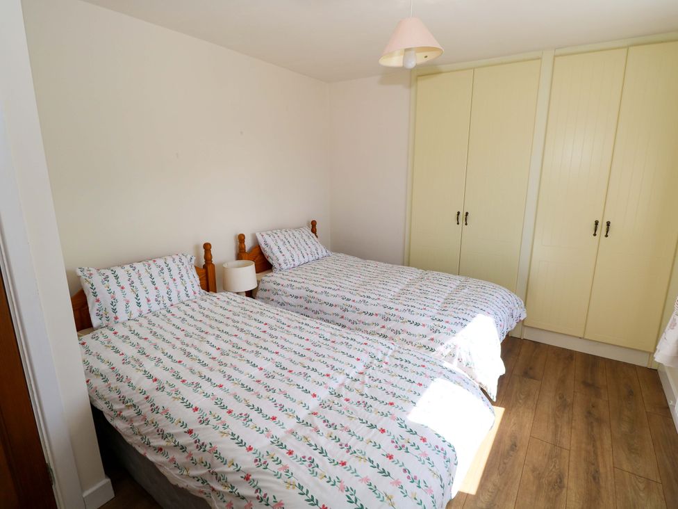 A bedroom with two single beds and a wardrobe at Cahir Cottage, Ballinrobe, County Mayo