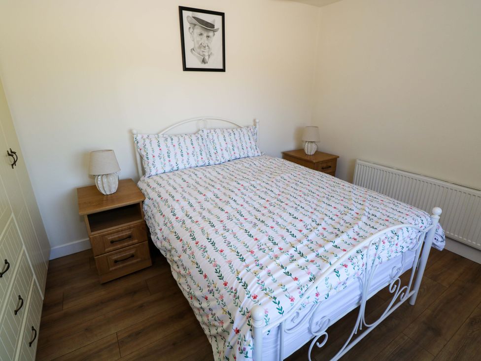 A bedroom with a bed, nightstands, and a wardrobe at Cahir Cottage Ballinrobe, County Mayo