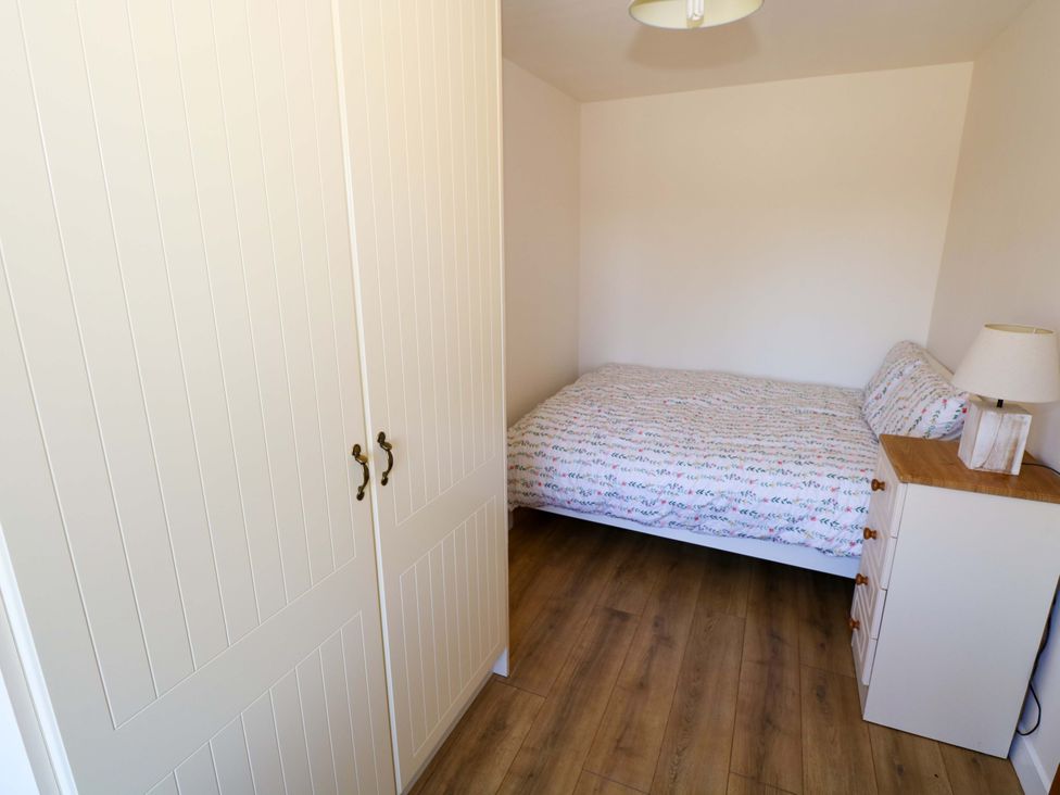 A bedroom with a bed and wardrobe at Cahir Cottage in Ballinrobe, County Mayo