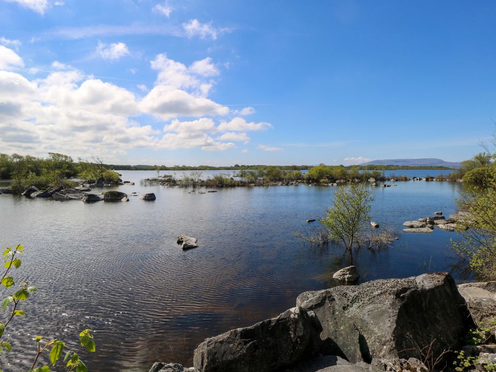 A view of a lake surrounded by trees and rocks at Cahir Cottage in Ballinrobe, County Mayo