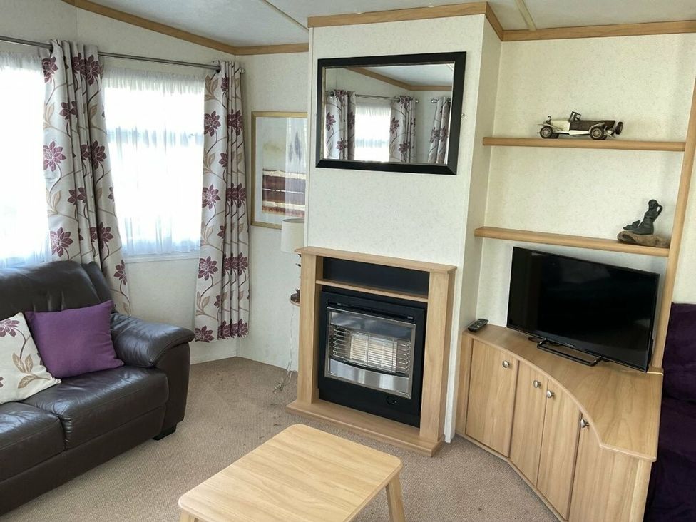 A living room with a sofa, coffee table, and television at St Monans Holiday Park - Holiday Accommodation 19927 in Anstruther
