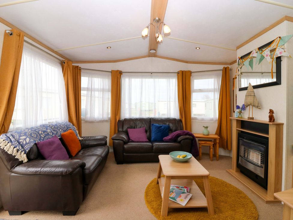A living room with a sofa, coffee table, and fireplace at St Monans Holiday Park - Holiday Accommodation 19927 in St Monans