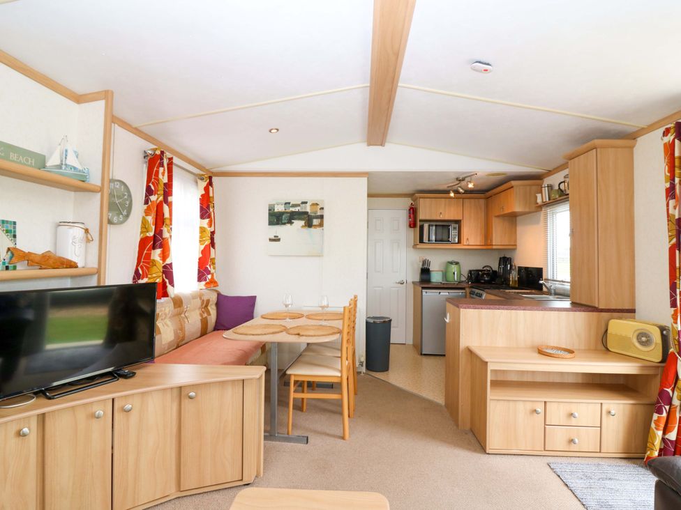 A living room and kitchen area with dining table and kitchen appliances at St Monans Holiday Park - Holiday Accommodation 19927 St Monans
