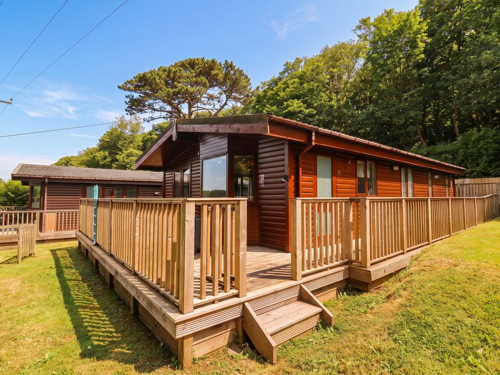 An outdoor view of a lodge with a wooden deck at Seagull Lodge in Watermouth near Combe Martin