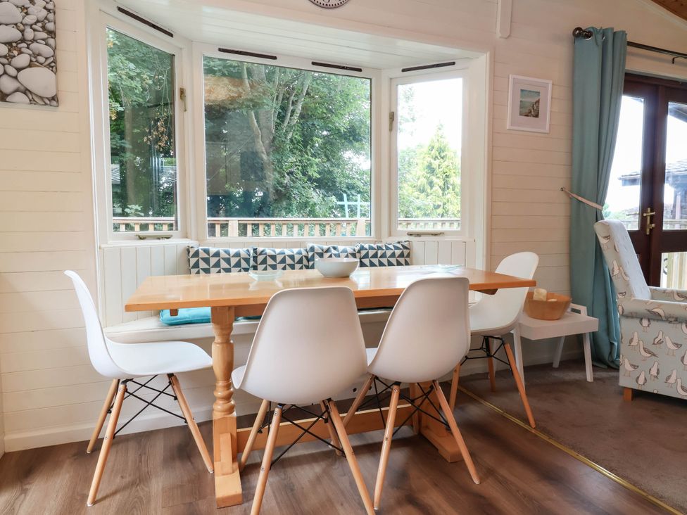 A dining room with a table and chairs at Seagull Lodge Watermouth near Combe Martin