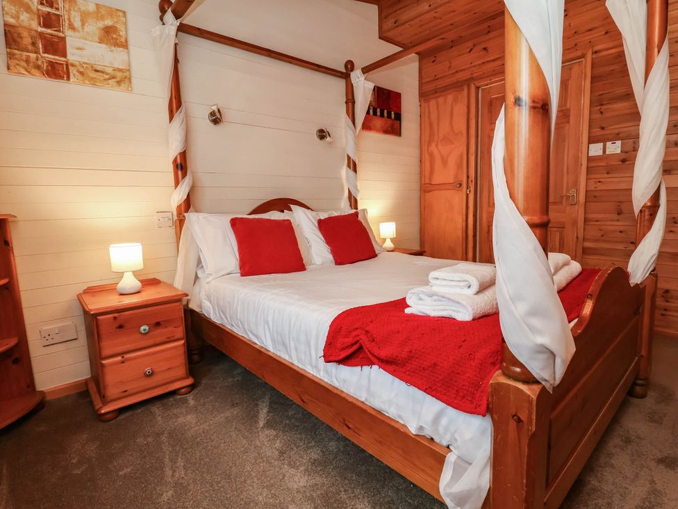 A bedroom with a four-poster bed and a bedside lamp at Seagull Lodge Watermouth near Combe Martin