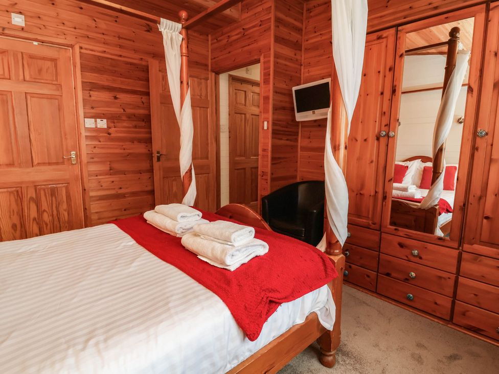 A bedroom with a bed and wardrobe at Seagull Lodge Watermouth near Combe Martin