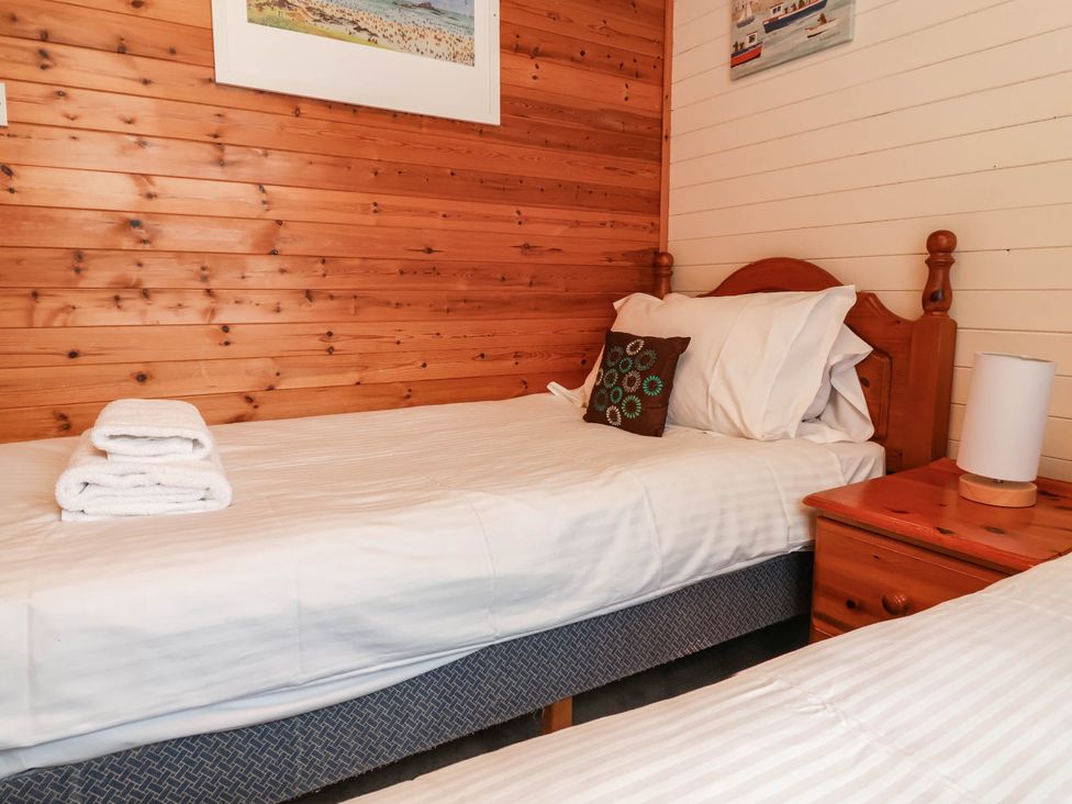 A bedroom with two single beds and a nightstand at Seagull Lodge in Watermouth near Combe Martin