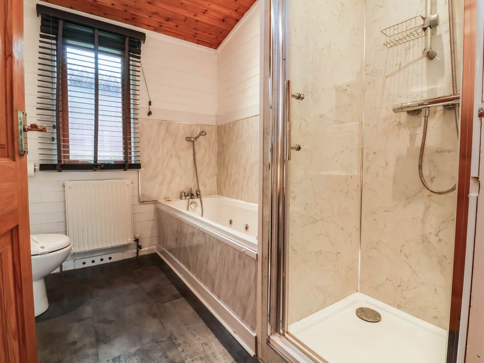 A bathroom with a bathtub, shower, and toilet at Seagull Lodge in Watermouth near Combe Martin