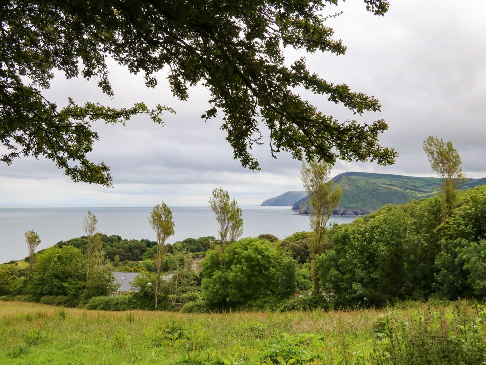 A view of the ocean and coastline with trees at Seagull Lodge in Watermouth near Combe Martin