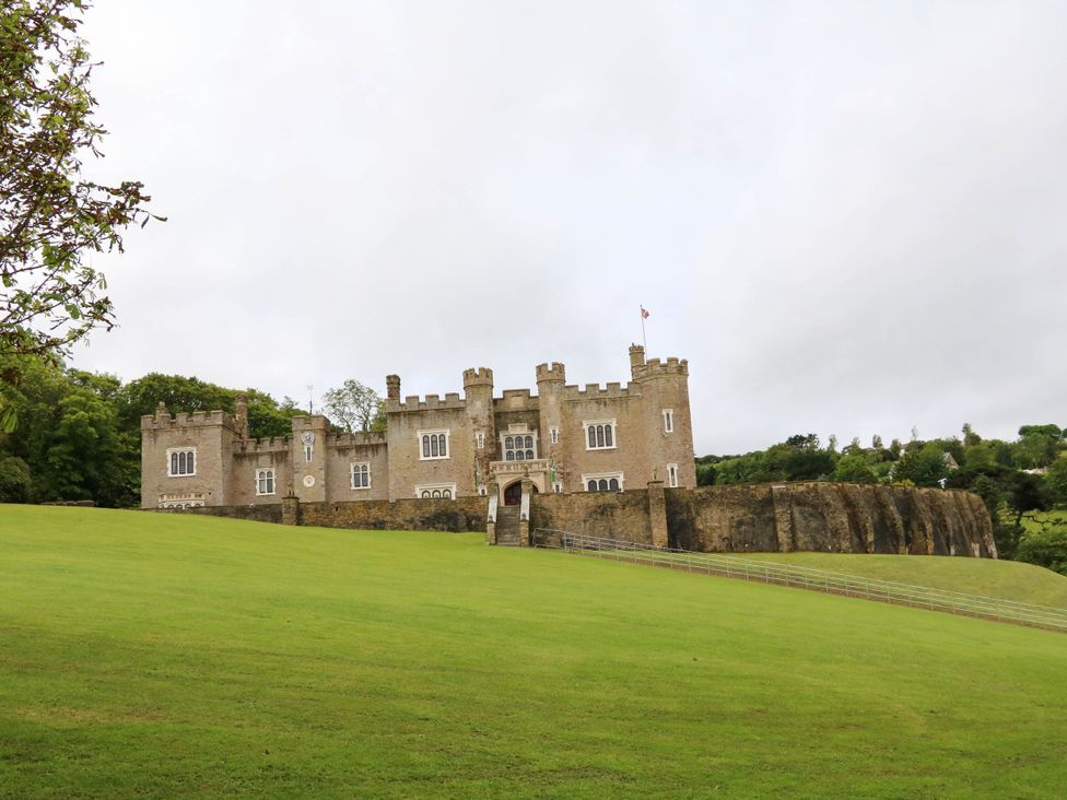 A castle on a hill with grass and trees at Seagull Lodge Watermouth near Combe Martin