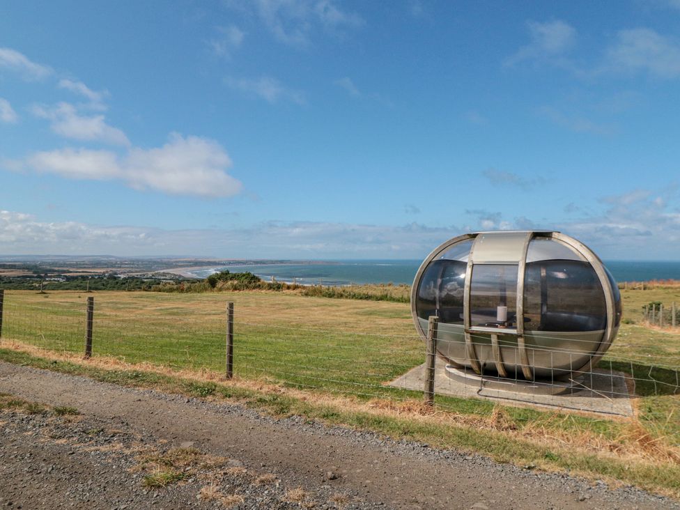 A round structure set in a grassy field overlooking the ocean at Bay View