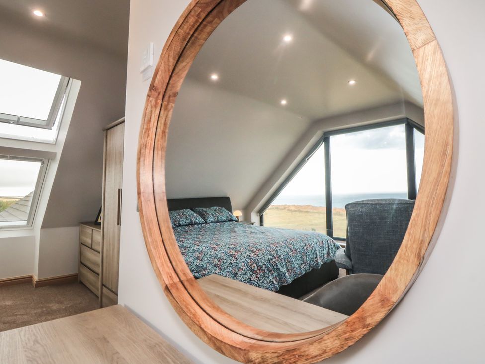 A bedroom with a bed and a mirror reflecting furniture and windows at Bay View