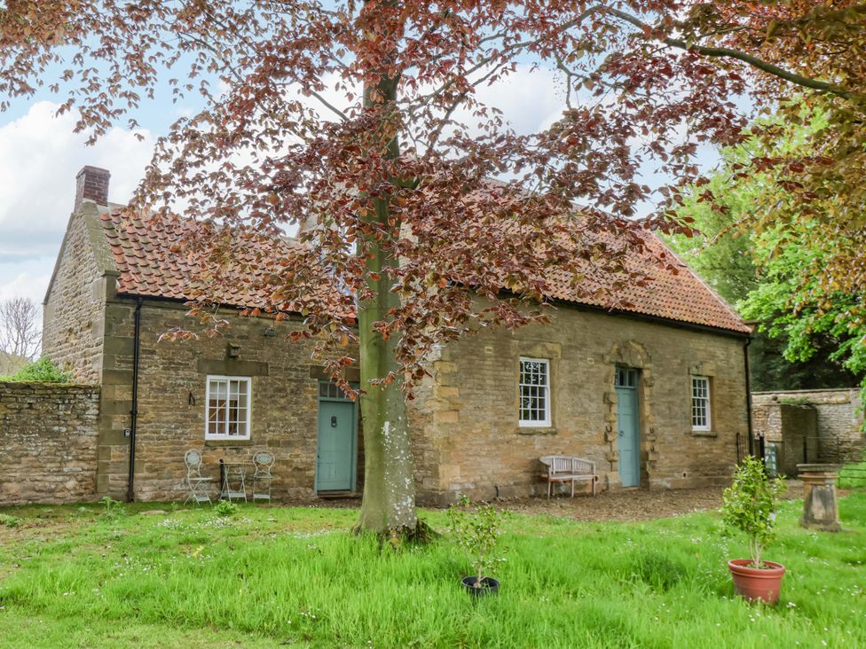 A cottage with a tree and seating area at The Gardener's Cottage, Low Hall Scarborough