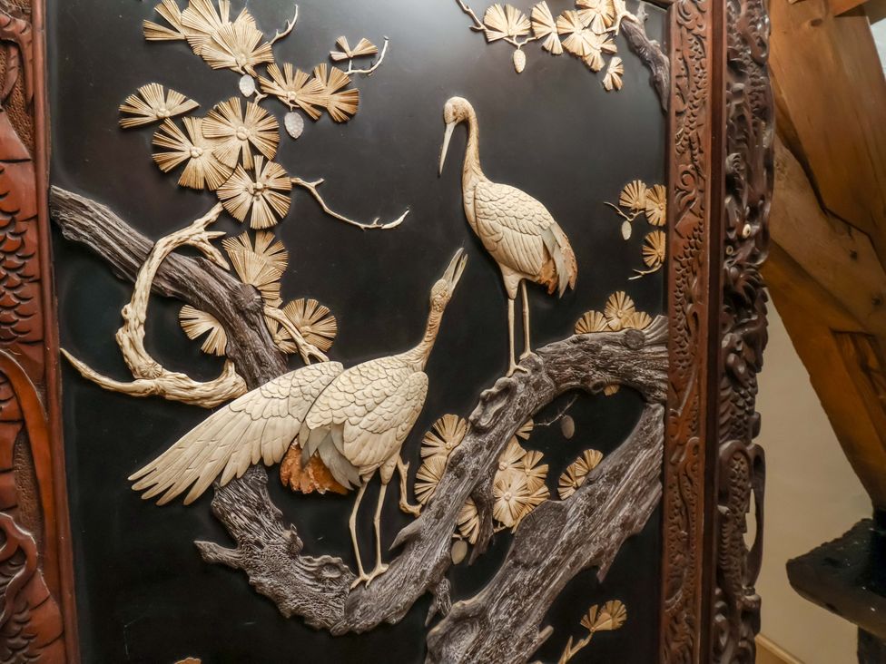 A carved wall panel featuring cranes and trees at The Gardener's Cottage, Low Hall Scarborough