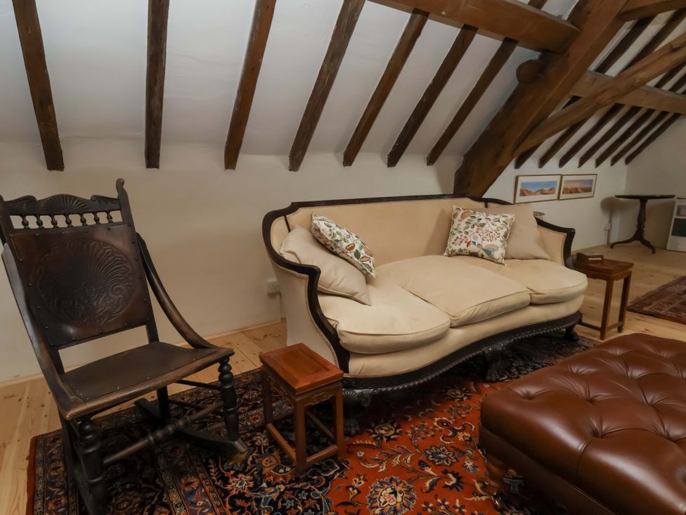 A living room with a sofa and rocking chair at The Gardener's Cottage, Low Hall Scarborough