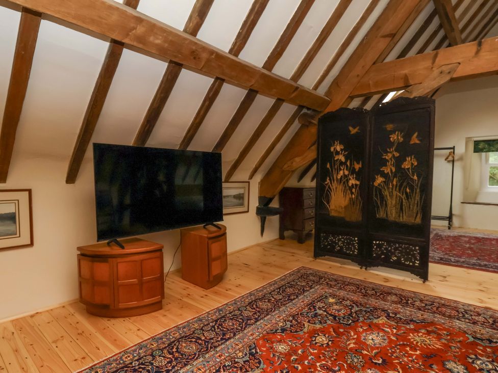A living room with a television and wooden beams at The Gardener's Cottage, Low Hall in Scarborough