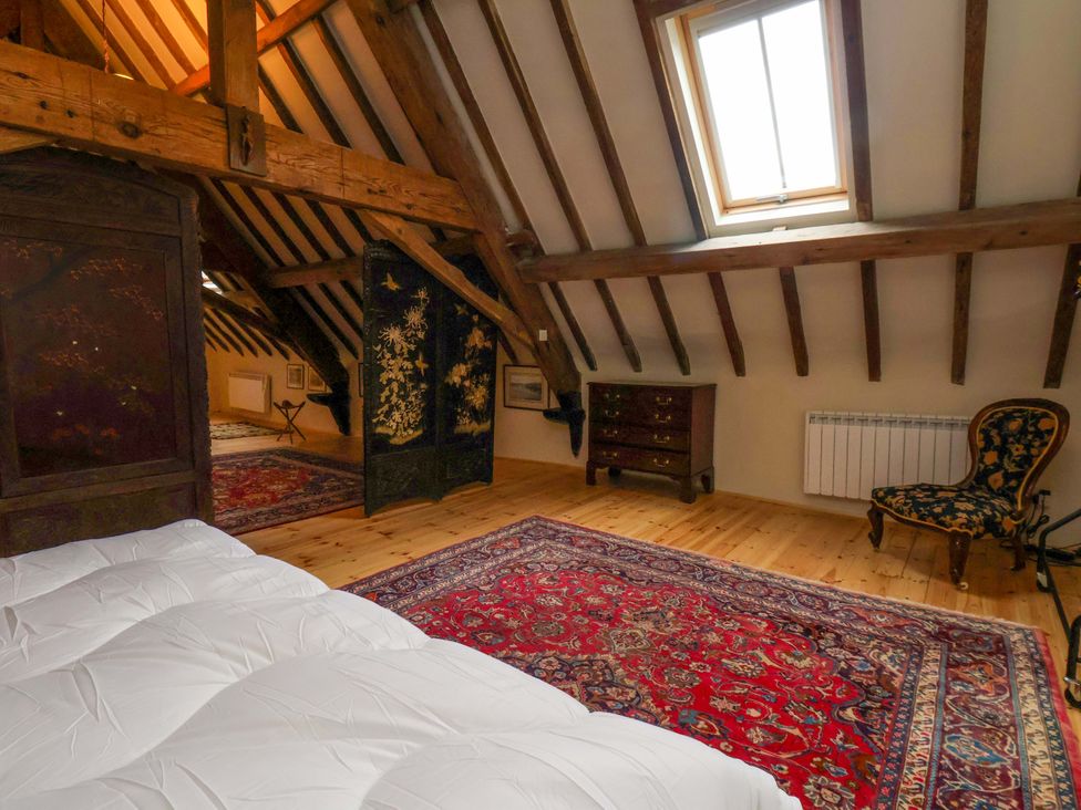 A bedroom with a bed and armchair at The Gardener's Cottage, Low Hall Scarborough