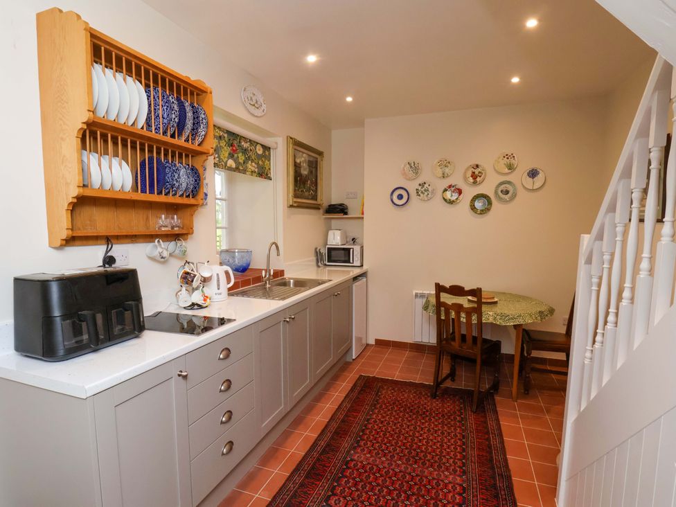 A kitchen with sink, plates, and table at The Gardener's Cottage, Low Hall Scarborough