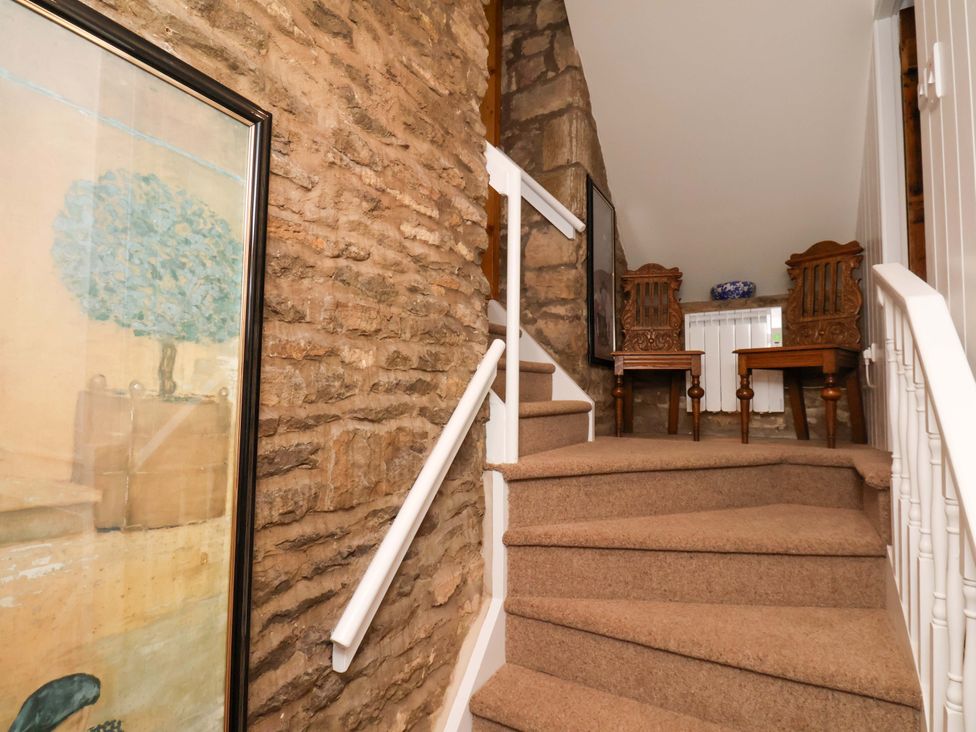 A staircase with artwork and wooden chairs at The Gardener's Cottage, Low Hall Scarborough