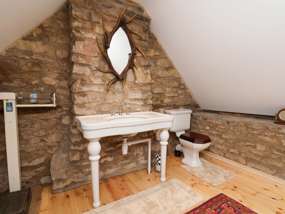 A bathroom with a sink, toilet, and mirror at The Gardener's Cottage, Low Hall Scarborough