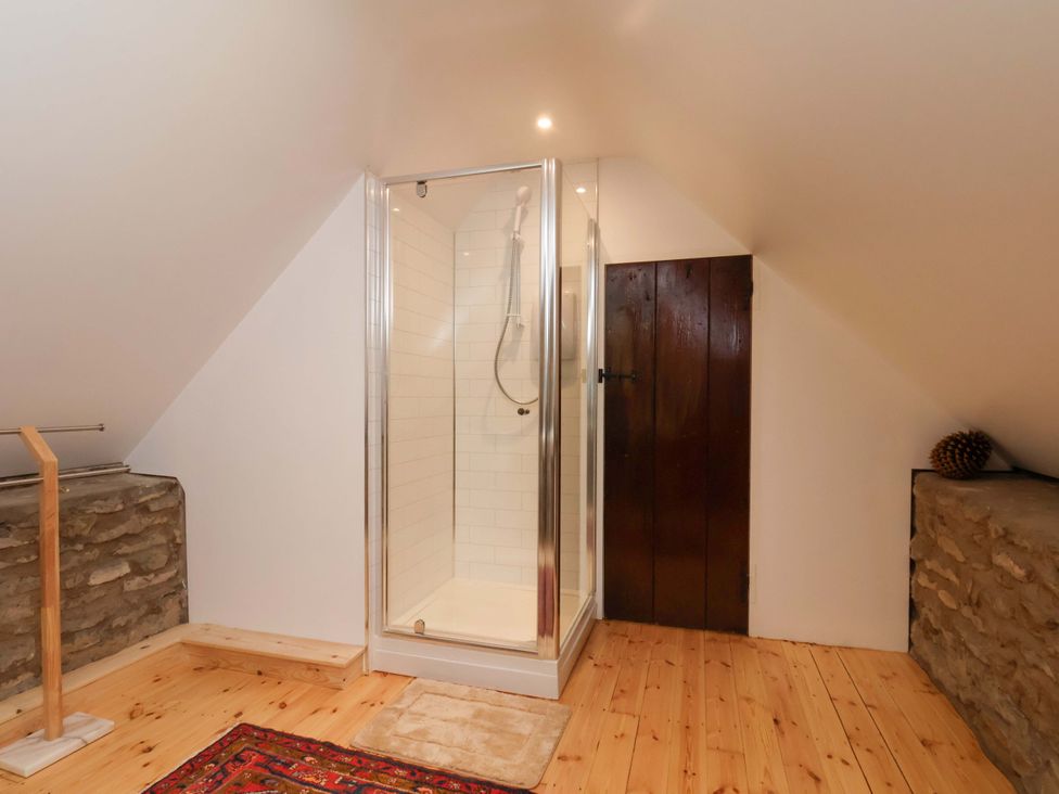 A bathroom with a shower and wooden door at The Gardener's Cottage, Low Hall Scarborough