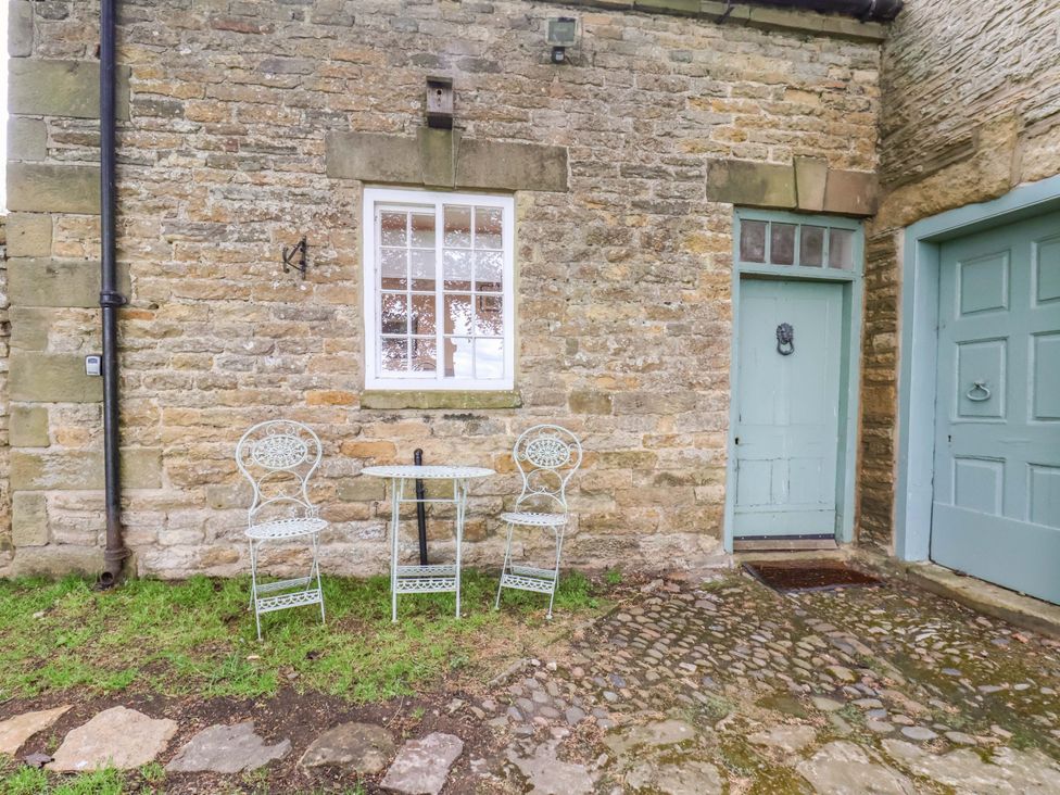 An outdoor area with a table and chairs beside a stone wall at The Gardener's Cottage, Low Hall Scarborough