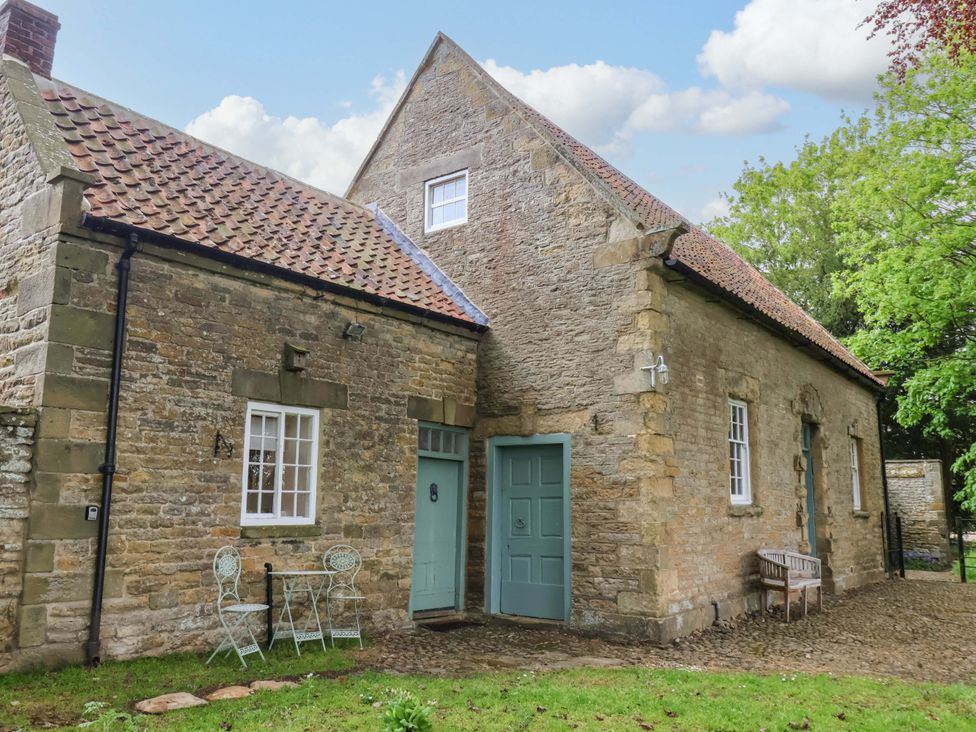 An exterior view of a stone cottage with a table and chairs at The Gardener's Cottage, Low Hall Scarborough