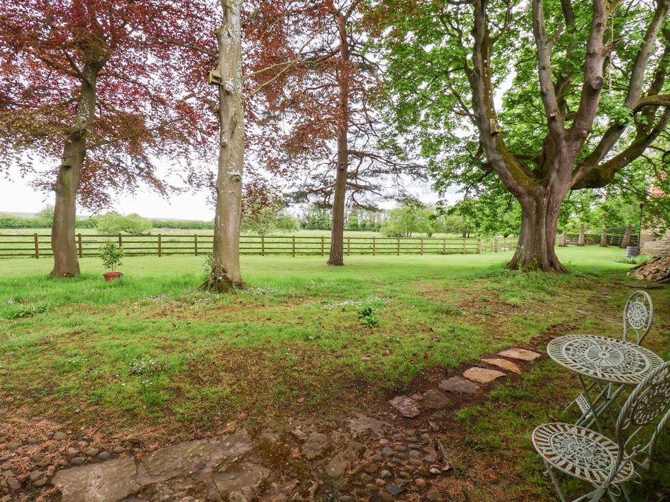 A garden with trees and a table set in The Gardener's Cottage, Low Hall Scarborough