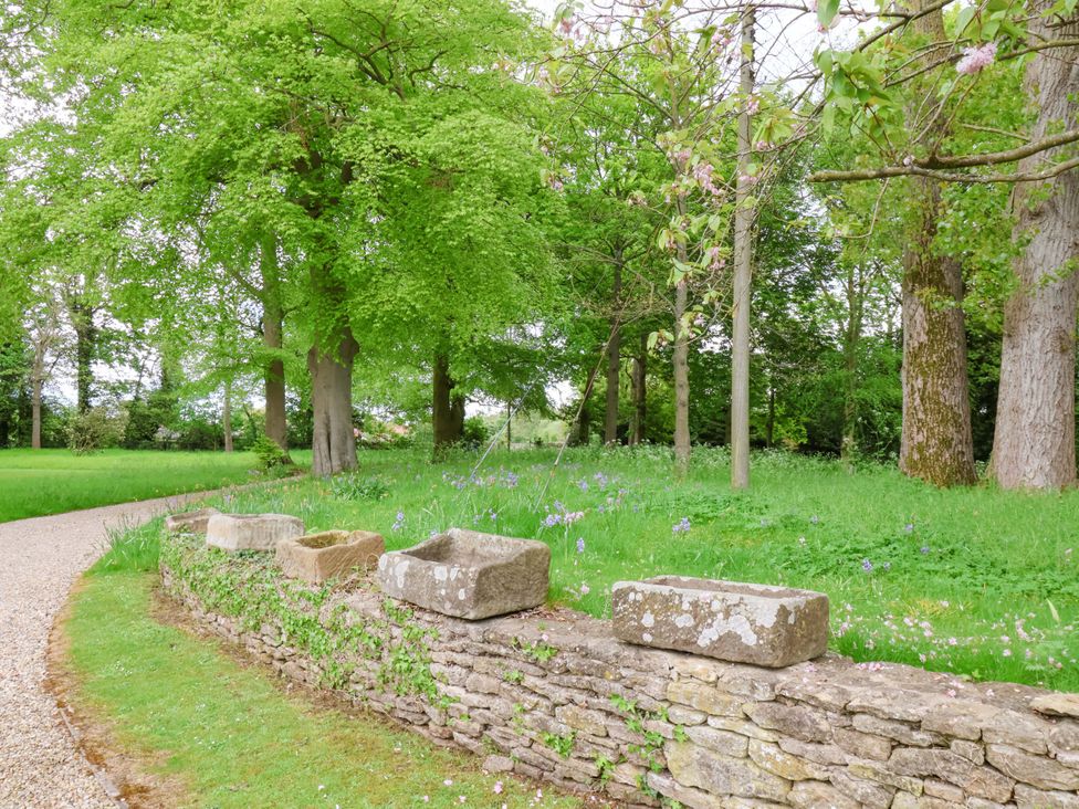 A garden with trees and a stone wall at The Gardener's Cottage, Low Hall Scarborough