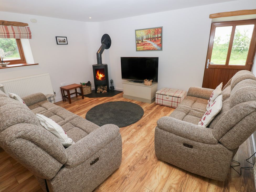 A living room with a sofa, rug, and television at The Gallops in Barry