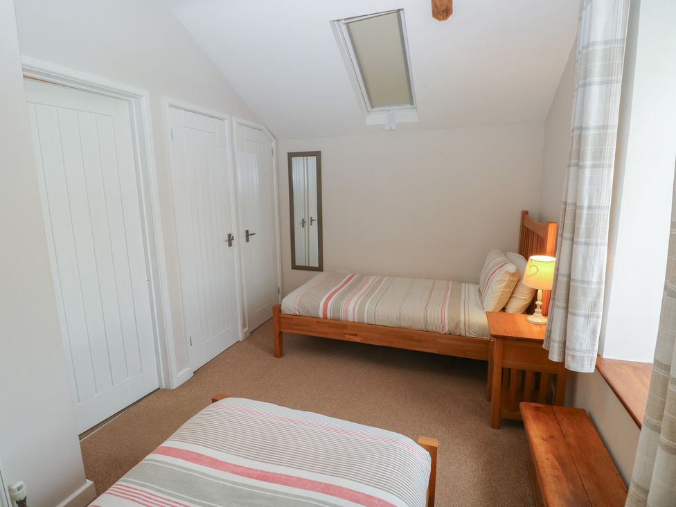 A bedroom with two beds and a lamp at The Gallops in Barry