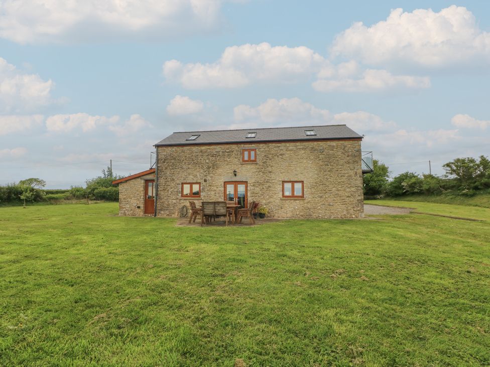 A house with a table and chairs on grass at The Gallops in Barry