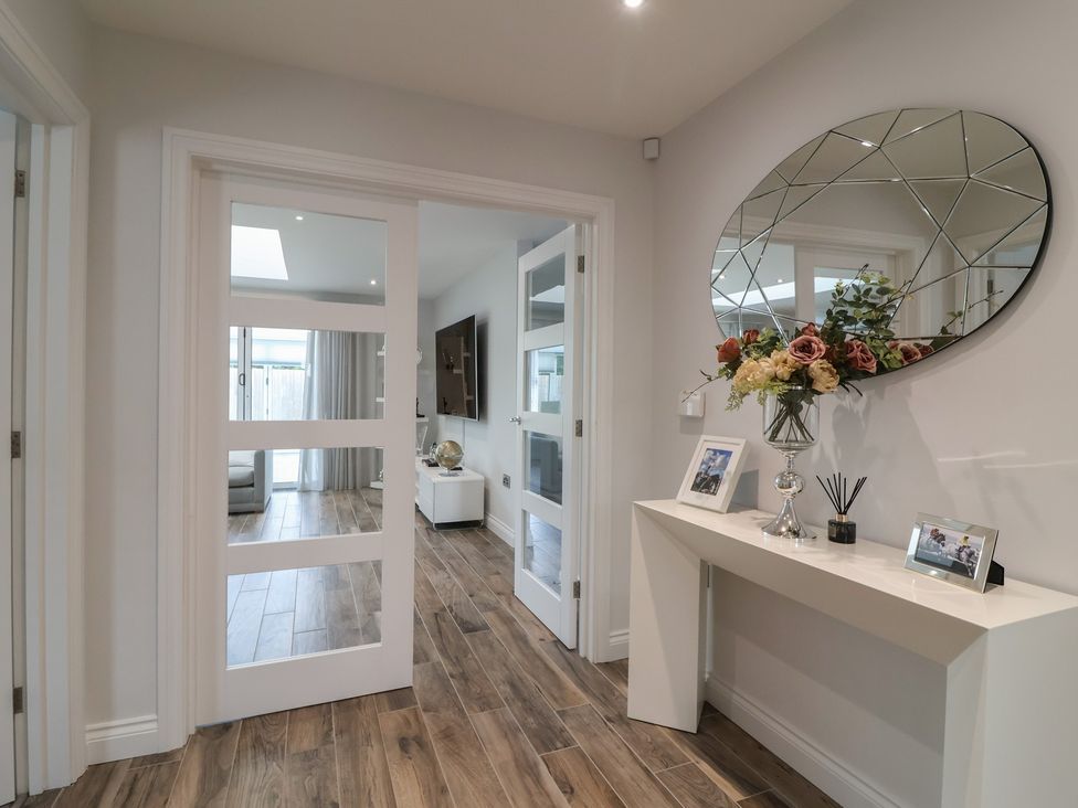 A hallway with a mirror and flower arrangement at Villina in Somerton