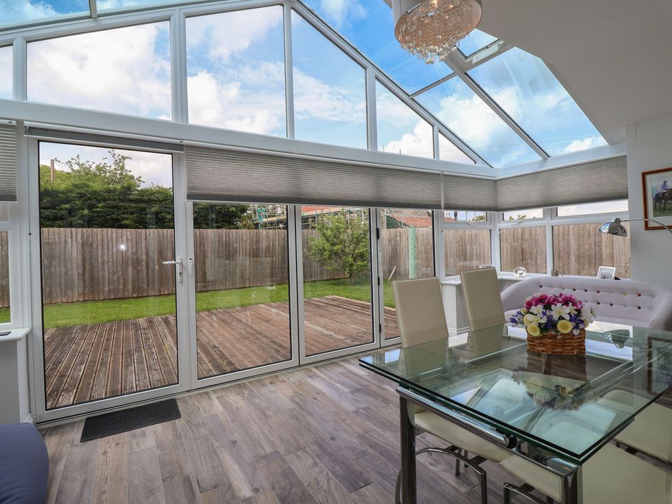 A conservatory with glass doors and a dining table at Villina in Somerton