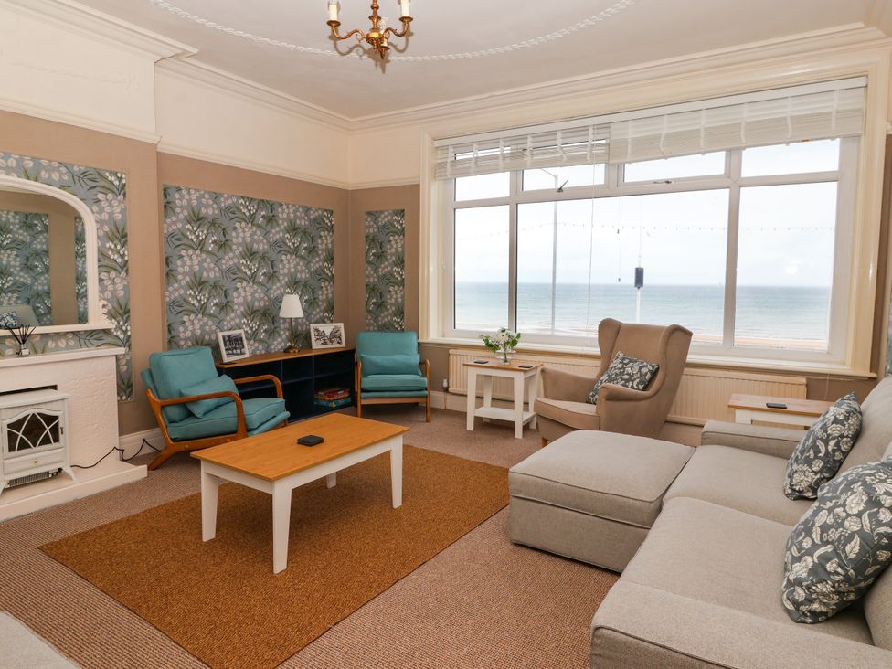 A living room with a sofa and chairs overlooking the sea at Sunrise Lodge in Bridlington